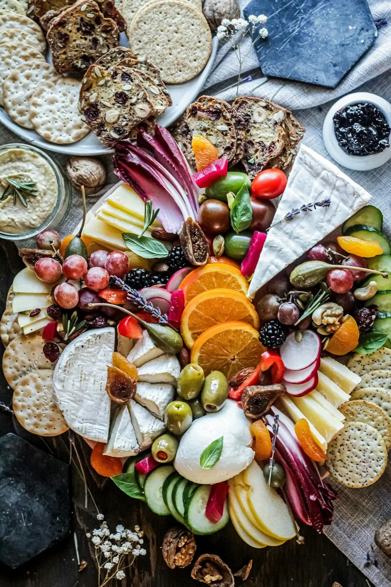 Overhead view of a shared board with cheese, fruit, nuts and crackers