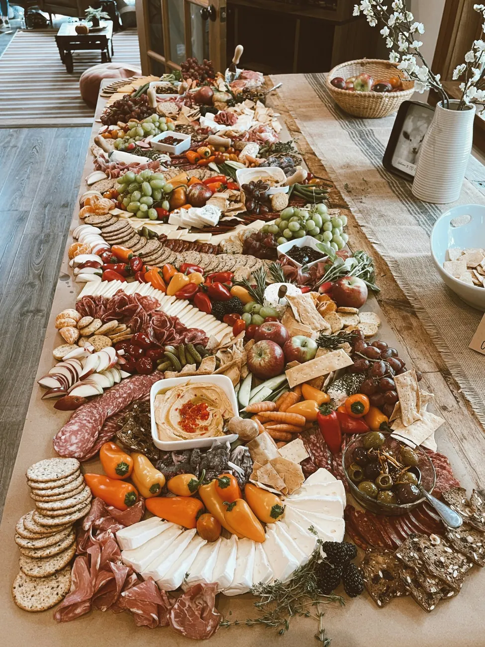 Long grazing table loaded with cheeses, cured meats, fruit and bread