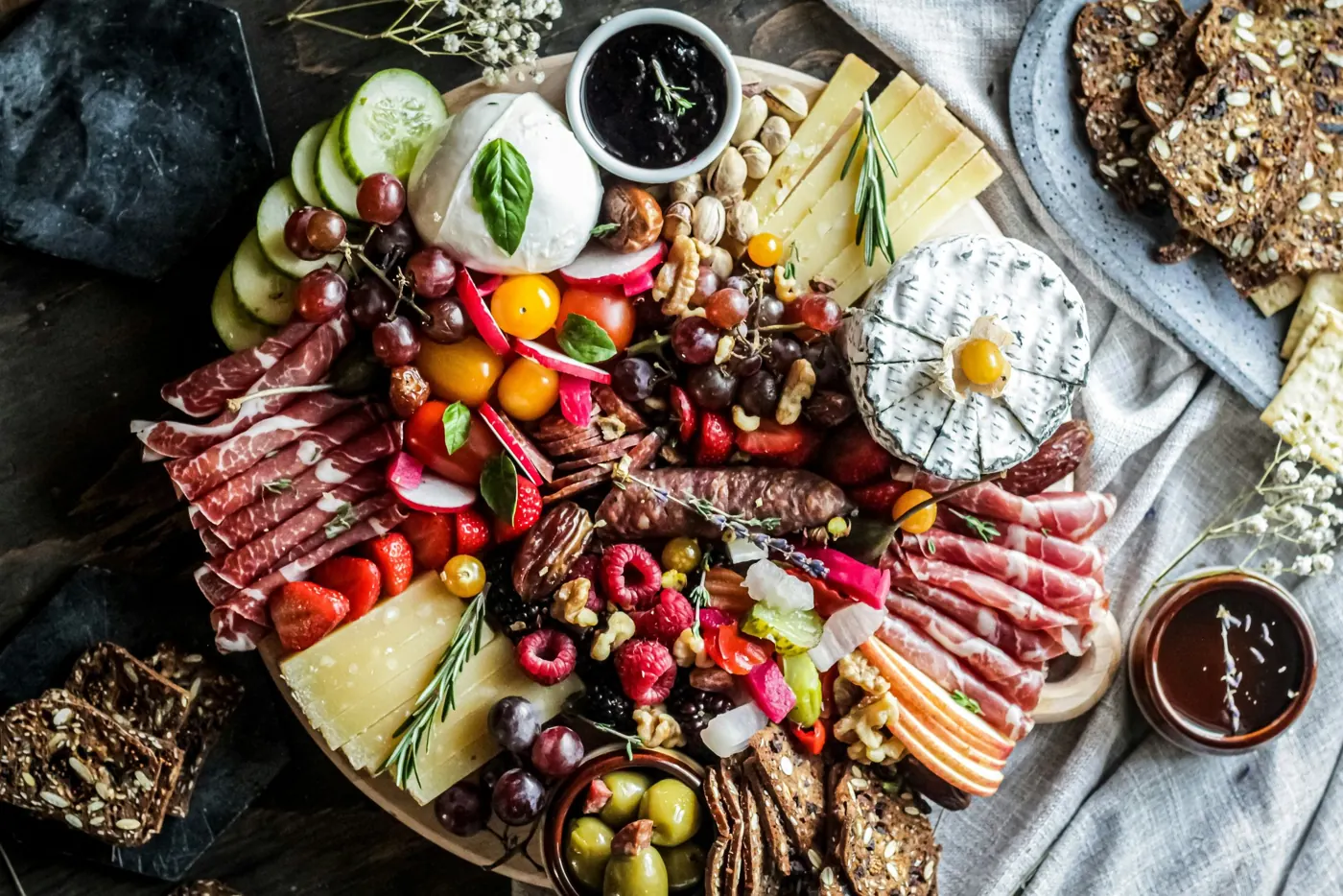 Overhead view of a round board with cheeses, cured meats, fruit and nuts