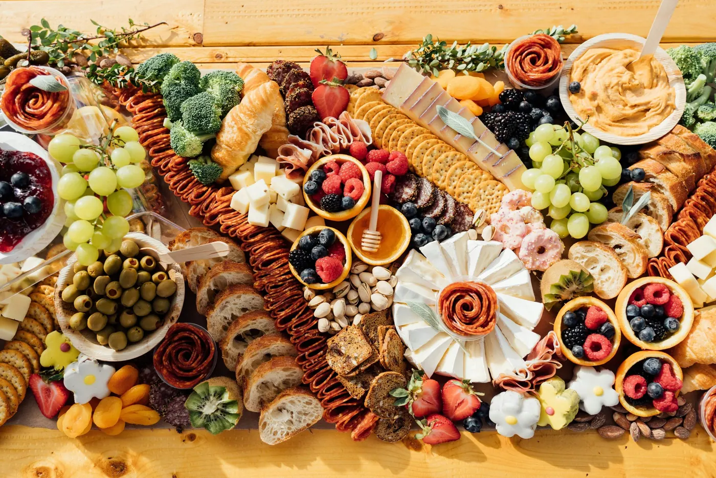 Long grazing table covered with boards of cheese, cured meats, fruit and bread