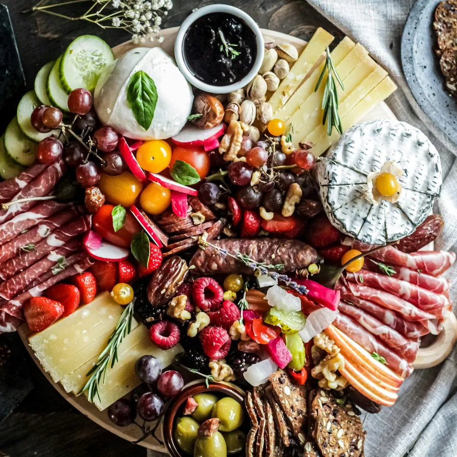A generous feast board of cured meats, cheeses and fruit
